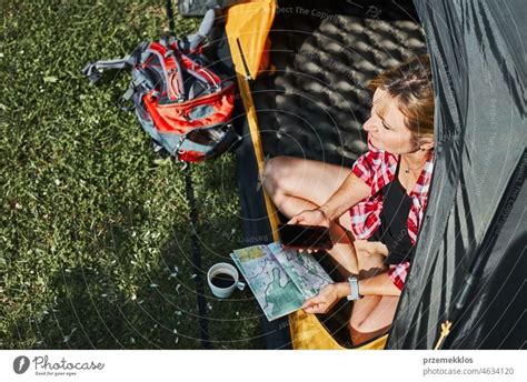 Frau plant nächste Reise während sie mit Karte im Zelt sitzt Frau
