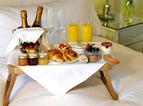 A Tray Filled With Food And Drinks On Top Of A White Bed Covered In Pillows