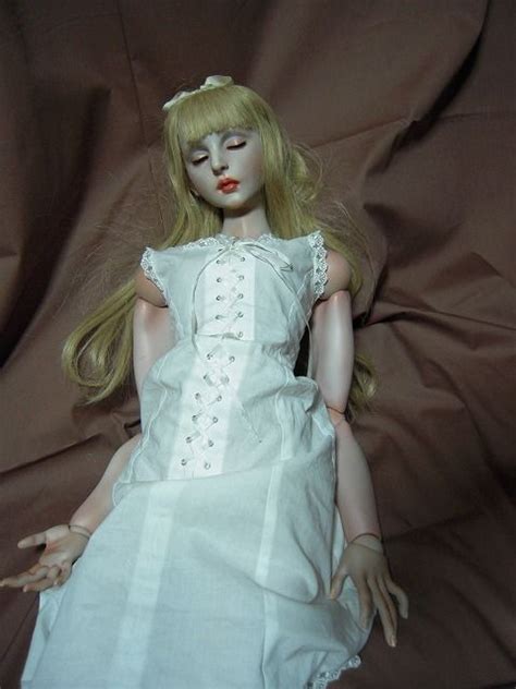A Doll With Blonde Hair Wearing A White Dress