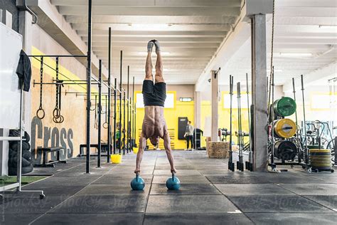 Sportsman Performing Handstand On Kettlebells In Gym Stock Image