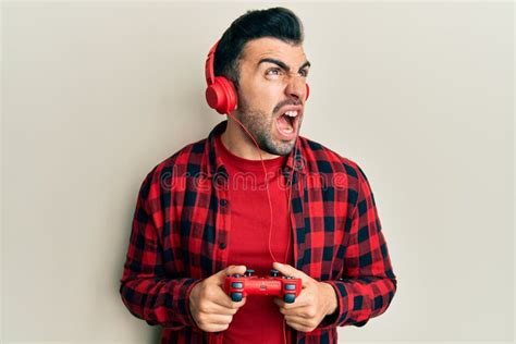 Young Hispanic Man Playing Video Game Holding Controller Angry And Mad
