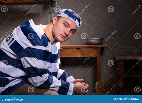 Young Male Prisoner Wearing Prison Uniform Looks At The Camera W Stock