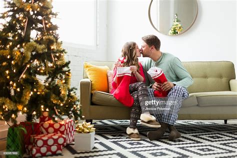 Young Couple With Christmas Stockings Kissing On Sofa Photo Getty Images