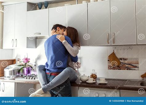 Happy Young Couple Hugging On Kitchen Woman Sitting On Table Stock
