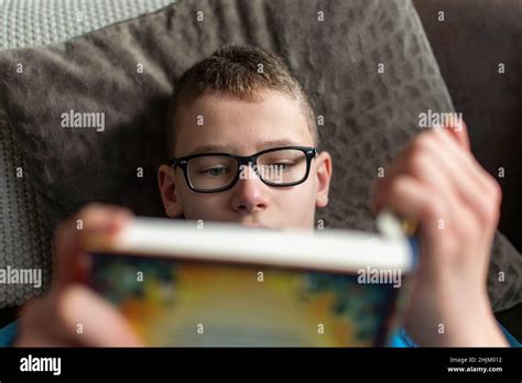 Child With Glasses On The Sofa Reading A Book Stock Photo Alamy