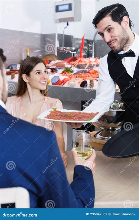 Handsome Waiter Bringing Delicious Carpaccio Of Raw Fish Stock Image