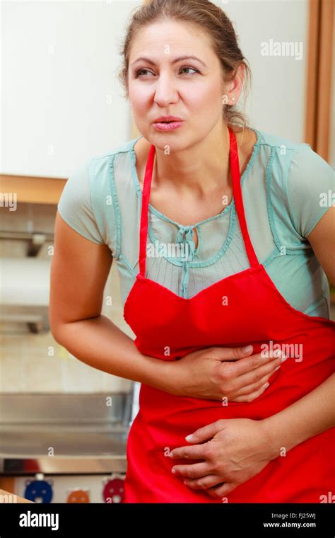 Mature Woman Suffering From Stomach Ache Abdominal Pain Middle Aged Female In Kitchen Stock