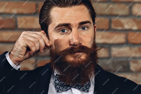 premium photo man wearing a suit hussar mustache and beard and posing against a brick wall