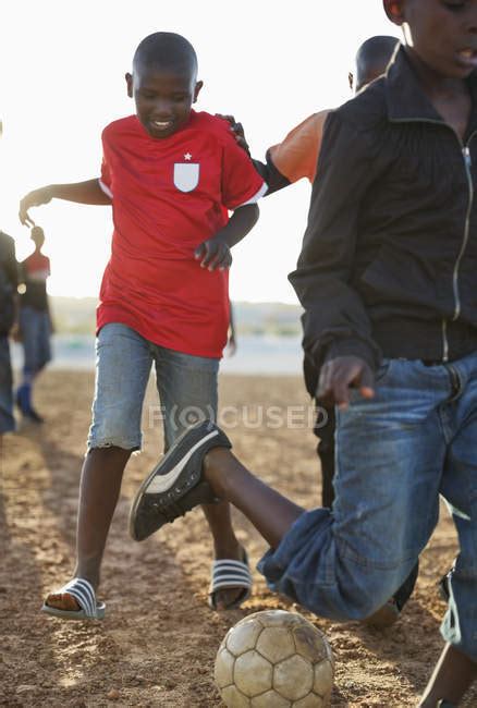 African Boys Playing Soccer Together In Dirt Field — African Ethnicity