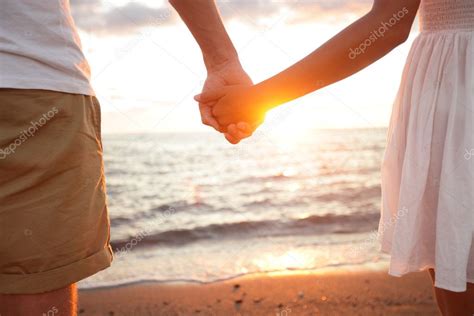 pareja de verano cogida de la mano al atardecer en la playa 2023