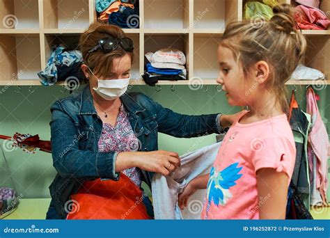 Child Changing Clothes In Changing Room In Nursery School Stock Photo