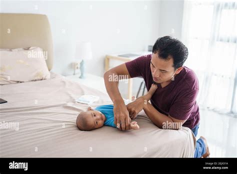 Portrait Of Asian Father Changing His Infant Baby Diaper At Home Stock