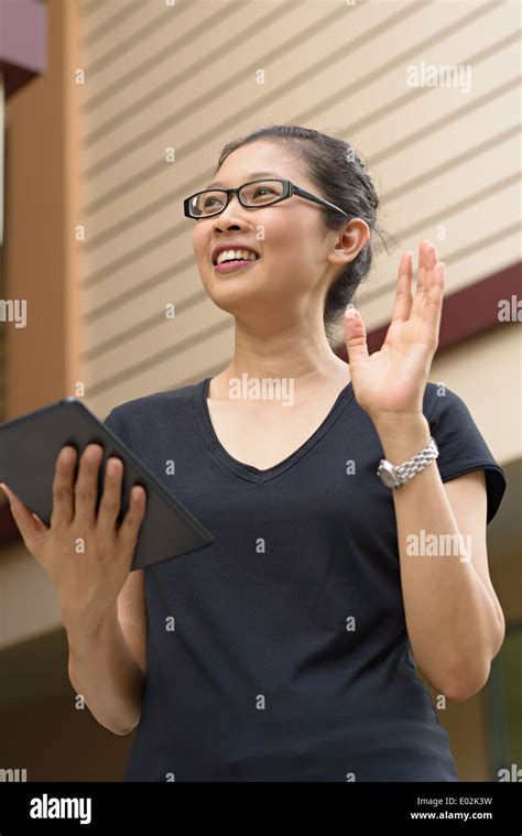 A Young Asian Woman Wearing Eyeglasses Holding An Ipad Tablet