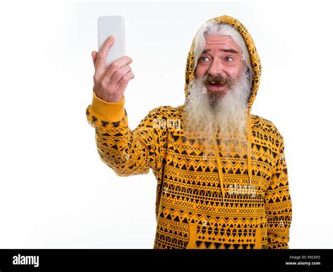 Studio Shot Of Happy Senior Bearded Man Smiling While Wearing Ho Stock