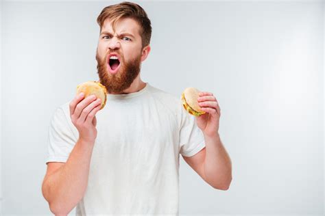Excited Bearded Man Greedily Eating Hamburgers Isolated On White
