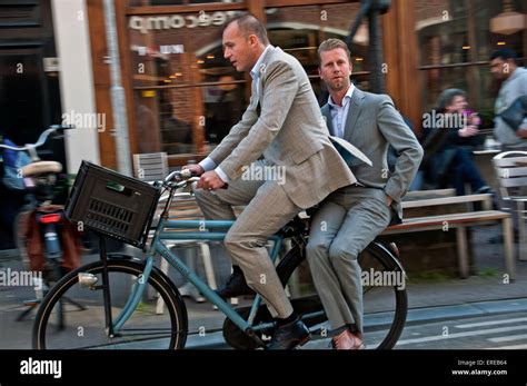 Two Men In Suits Riding Together On Bicycle In Amsterdam Stock Photo