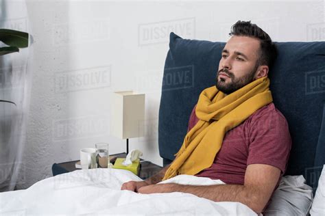 Depressed Sick Young Man Lying In Bed And Looking Away