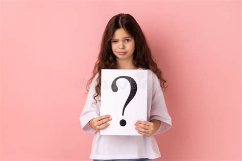 Winsome Little Girl Looking At Camera Holding Paper With Question Mark
