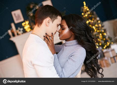 Cute Interracial Married Couple On A Festive Christmas Evening Decorated Interior For The New