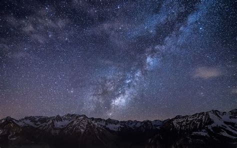 The Night Sky Is Filled With Stars Above Mountains And Snow Capped