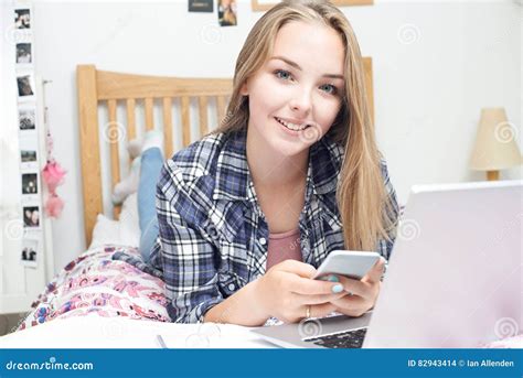 Adolescente Que Usa O Telefone Celular Enquanto Fazendo Trabalhos De Casa Foto De Stock Imagem