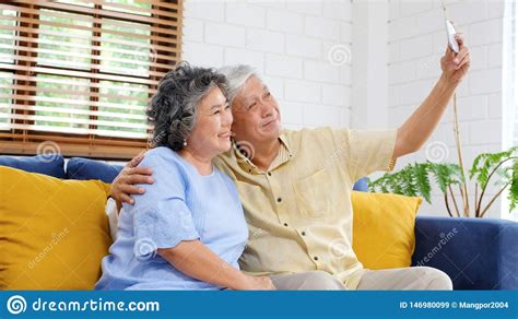 Happy Senior Asian Couple Taking Selfie At Home Living Room Active