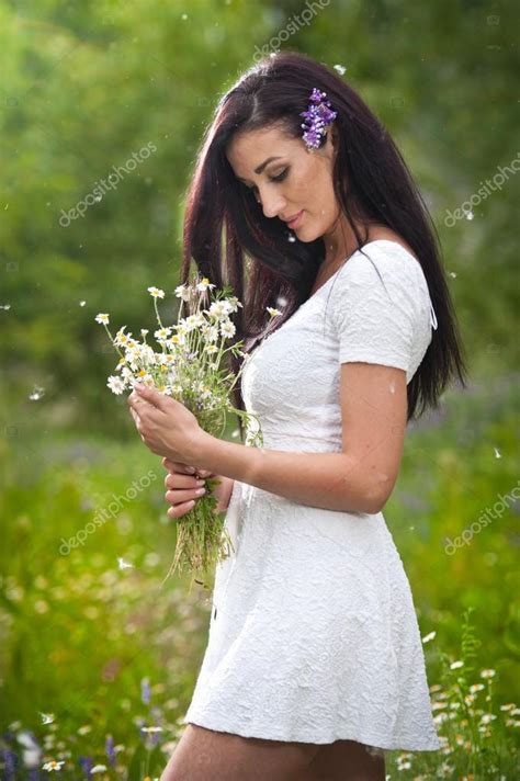 Young Beautiful Brunette Woman Holding A Wild Flowers Bouquet In A Sunny Day Portrait Of