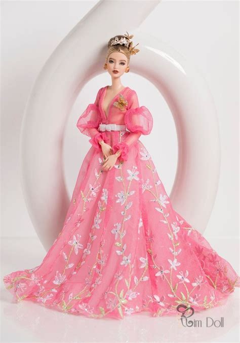 A Barbie Doll Wearing A Pink Dress And Holding A Flower In Front Of A White Background