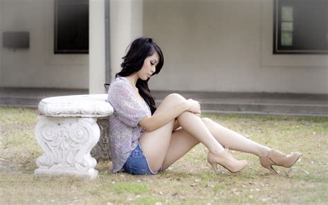 Brunette Sitting On The Ground Near A Stone Bench