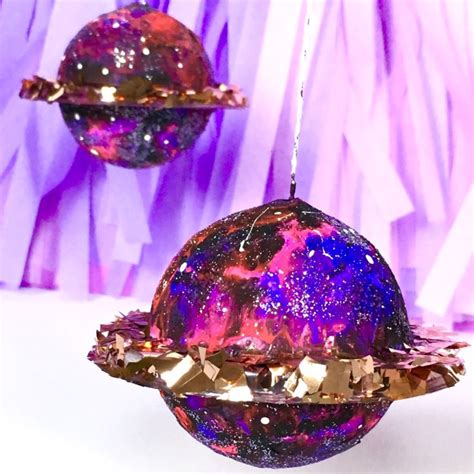 An Ornament Hanging From A String In Front Of Some Purple And Gold
