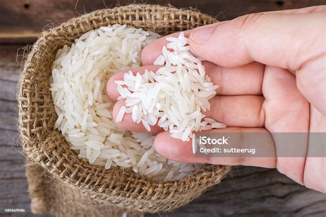 Womans Hand Picking Uncooked Rice In A Small Burlap Sack Stock Photo