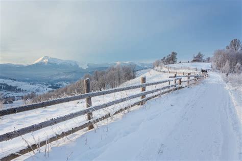 Winter Country Landscape With Timber Fence And Snowy Road Stock Photo
