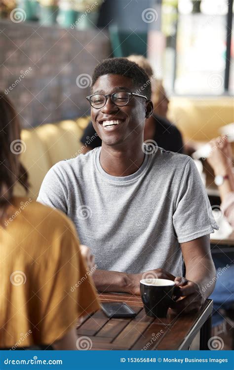 Couple Sitting At Table In Busy Coffee Shop Talking Stock Photo Image