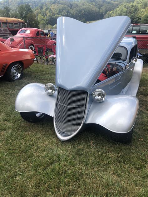an old car with its hood open on display at a car show in the grass