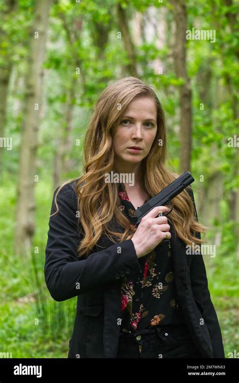 Red Haired Young Woman Wearing Black And With A Hand Gun Pistol In The