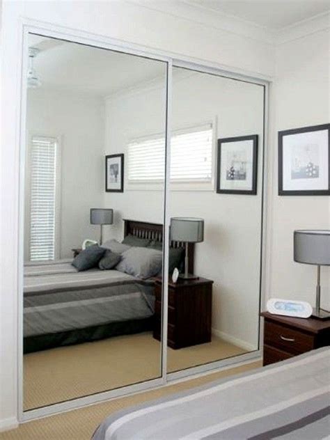 A Bedroom With Mirrored Closet Doors And A Bed In The Corner Along With Pictures On The Wall