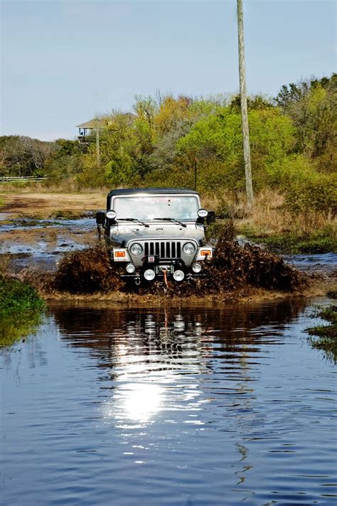 A Jeep Is Driving Through Some Mud In The Middle Of A Body Of Water