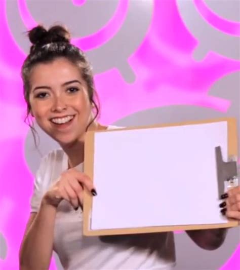 A Woman Holding Up A White Board In Front Of A Pink Background