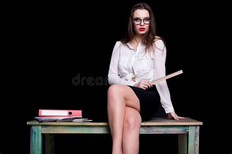 Seksowny Nauczyciel Pozuje Na Biurku W Studiu Na Czarnym Tle Zdjęcie
