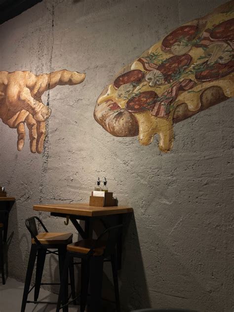 Two Tables And Stools In Front Of A Wall With Pizza Paintings On The Walls