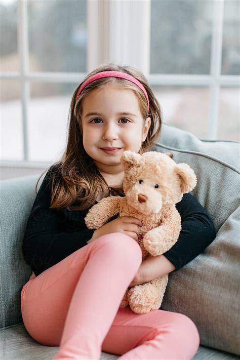 Beautiful Young Girl Sitting On A Big Chair With Her Teddy Bear Del Colaborador De Stocksy