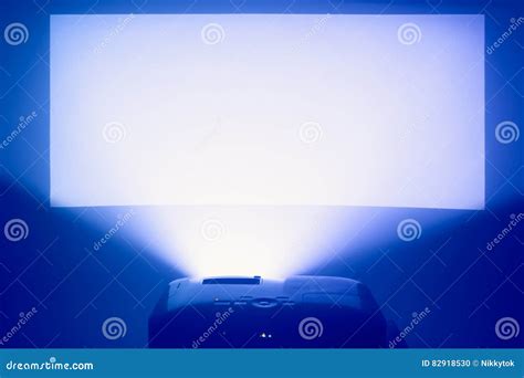 Projector In Action With Illuminated Warm Blue Screen Stock Photo