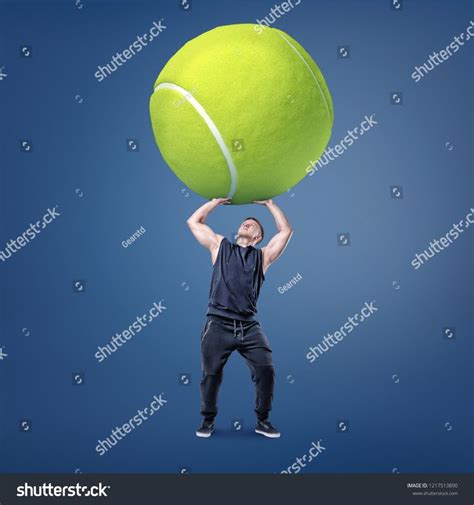 A Small Young Muscular Man Tries To Hold A Giant Yellow