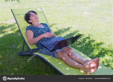 Happy Mature Woman Relaxing Resting On The Deck Chair In Garden Stock