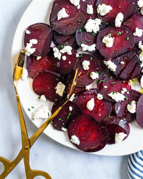 Beets And Goat Cheese On A White Plate With Gold Handled Utensils Next
