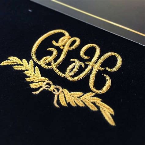 an embroidered monogram is shown on a black velvet surface with gold trimmings