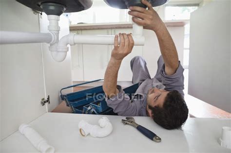 Plumber Working On Pipes Under Kitchen Sink — Installation Installing