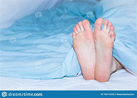 Men S Feet Sticking Out From Under The Blue Blanket Stock