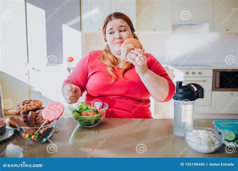 Fat Young Woman In Kitchen Sitting And Eating Junk Food Plus Size