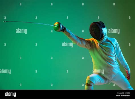 Energetic young man, fencer with smallsword practicing fencing isolated